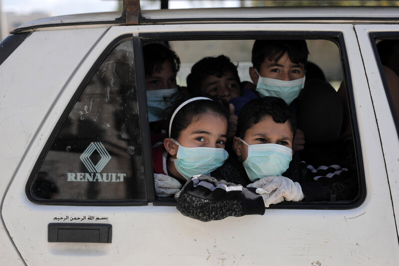 Children wearing face masks look out of vehicle window 