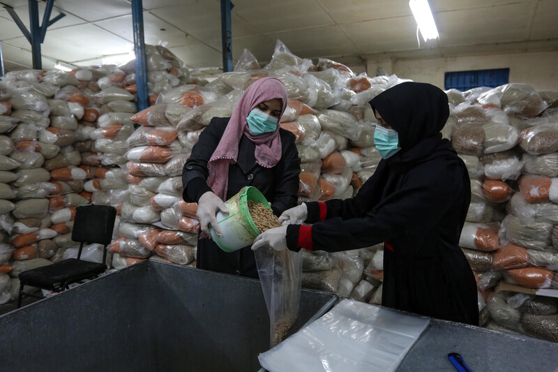 Women pour dry beans into bags