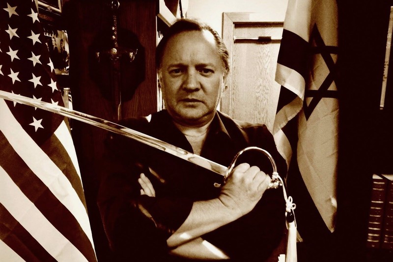 Man with sword flanked by US and Israeli flags