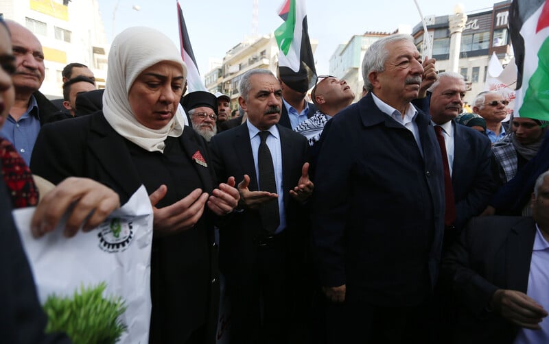 A crowd of people turn their palms upward in prayer