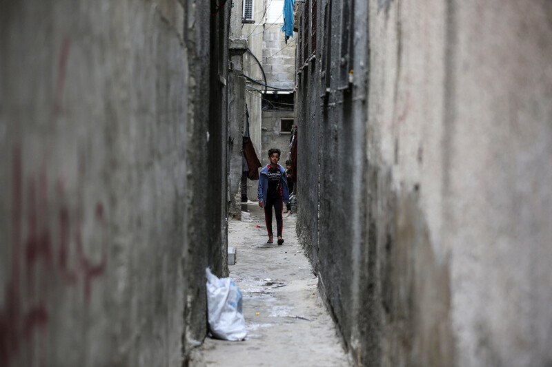 Walls tower over a child in a narrow passage