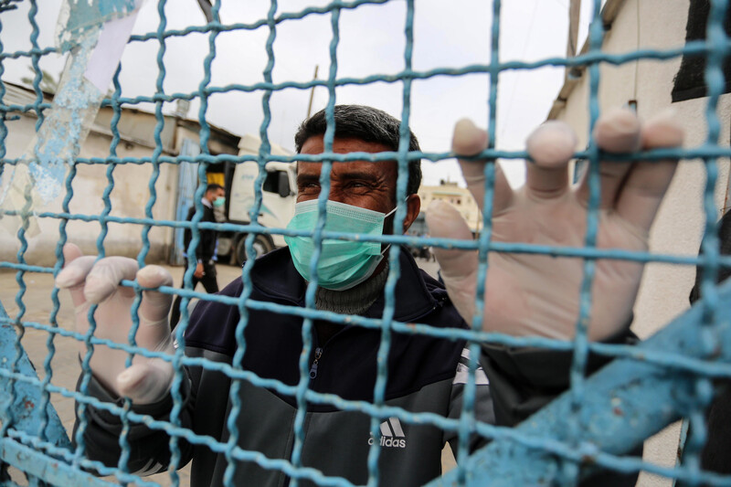 Man wearing face mask holds barbed wire