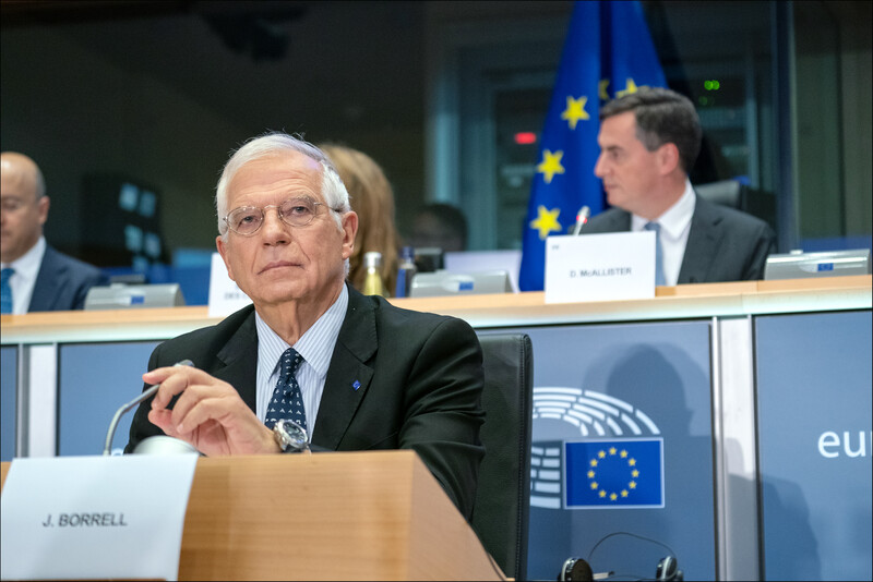 Man sits at podium touching microphone