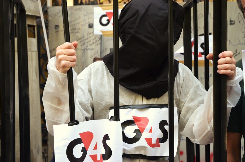 A protester wears a hood behind bars