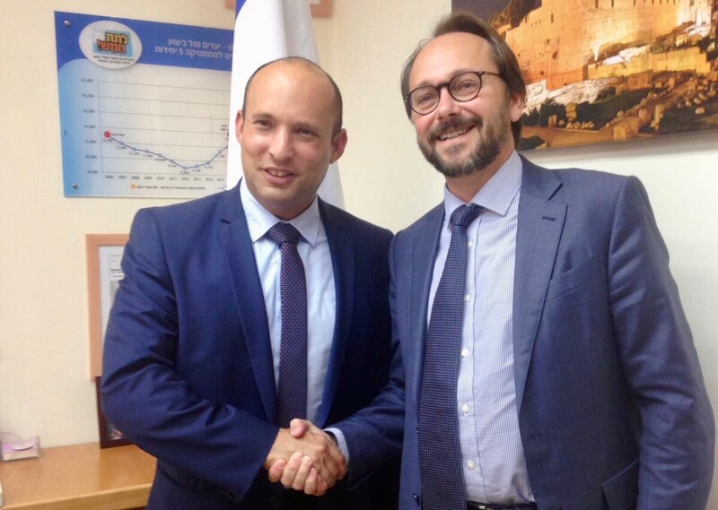 Two men in suits smile and shake hands