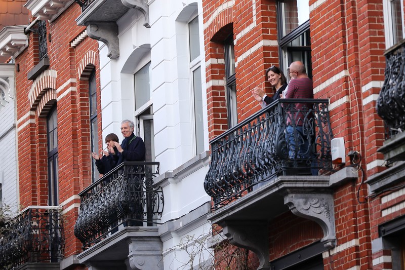 Smiling people clap on adjacent balconies