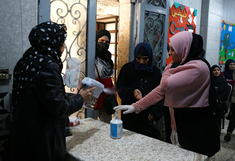 A woman sprays another woman's hands as two women look on