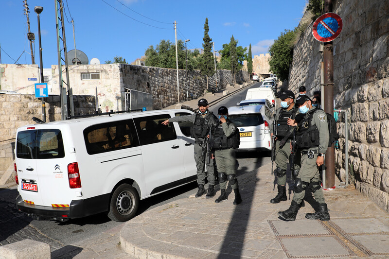 Armed soldiers in protective masks stand near vans