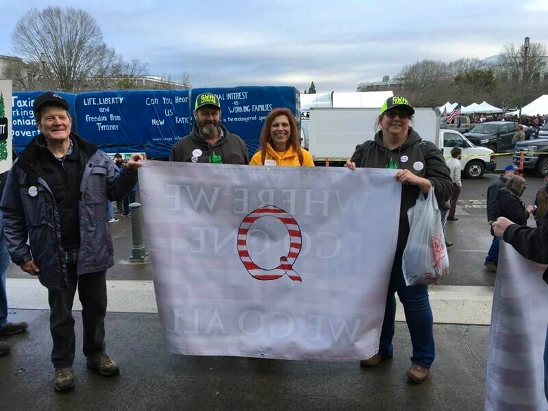 People stand with QAnon banner