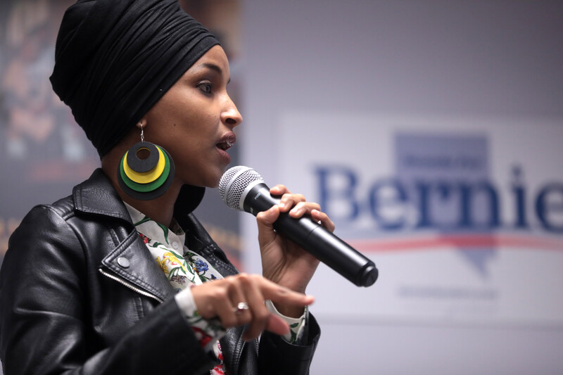 Woman holds microphone with one hand and gestures with the other