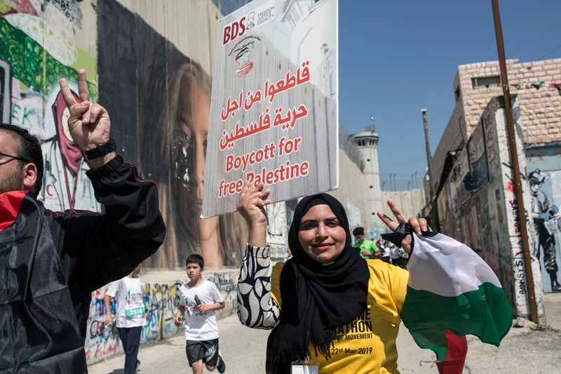 A woman makes a victory sign while holding a poster