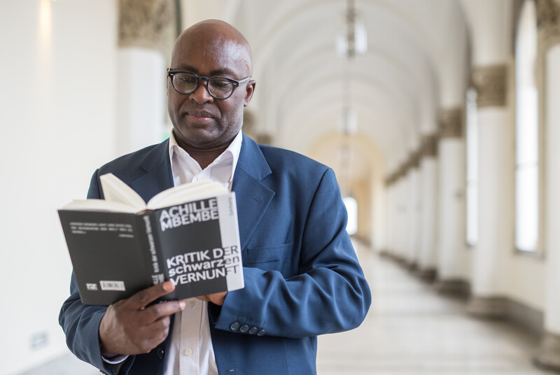 A standing man reads a book