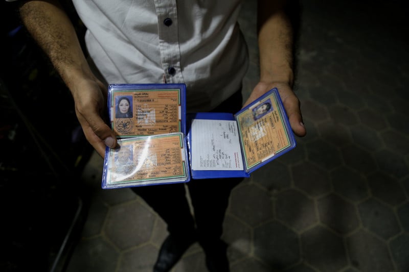 A man holds temporary ID cards that are void for travel.