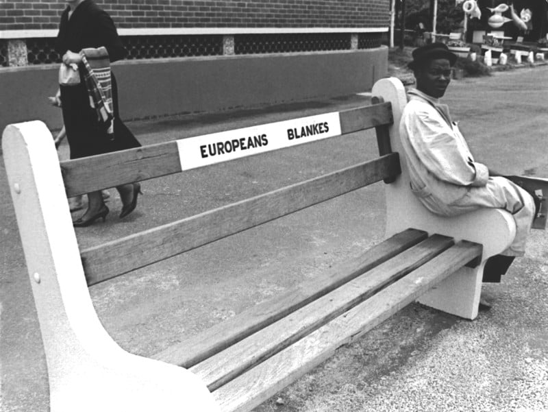 Man sits on edge of bench that says Europeans Only