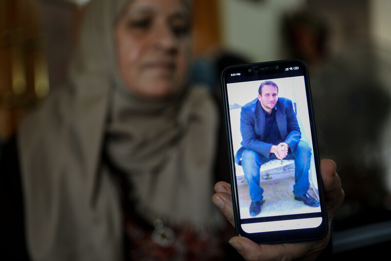 A woman holds out a mobile phone showing a picture of a man