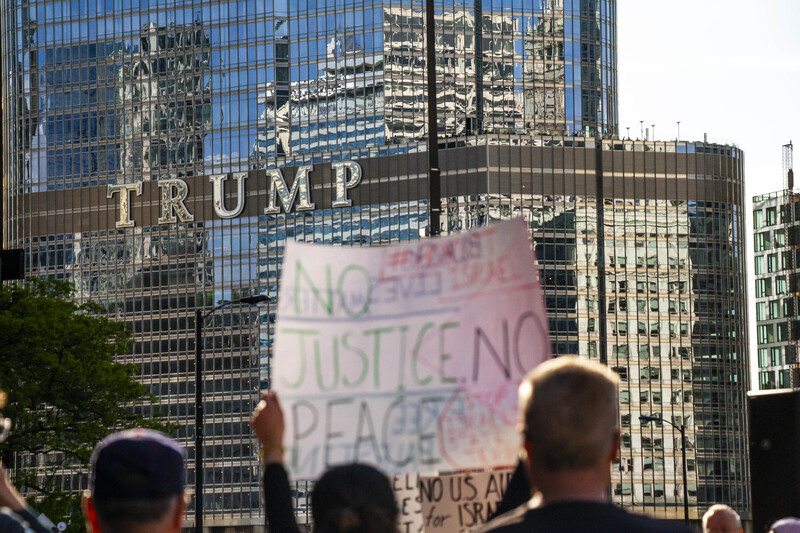 People hold protest signs in front of Trump building