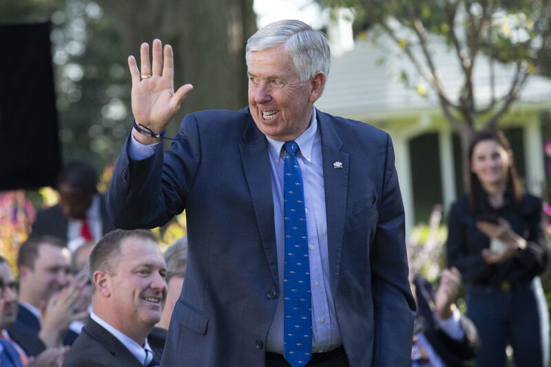 A man in a suit waves his hand