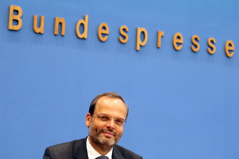 Smiling man sits a press podium