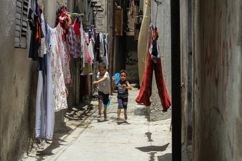 Two children play in a narrow alley where washing has been hung