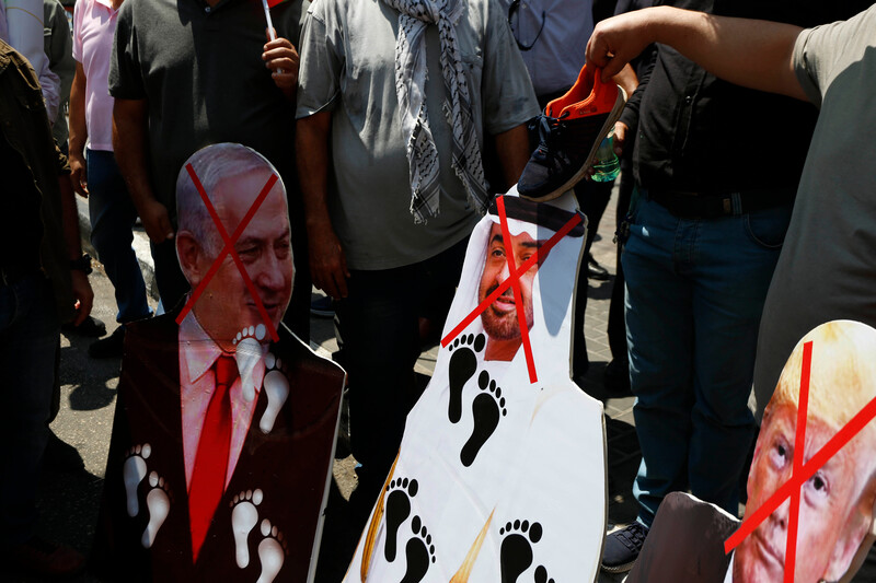 People hold images of regional leaders with foot marks on them