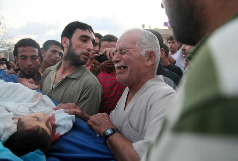 Man cries over body of child as others look on