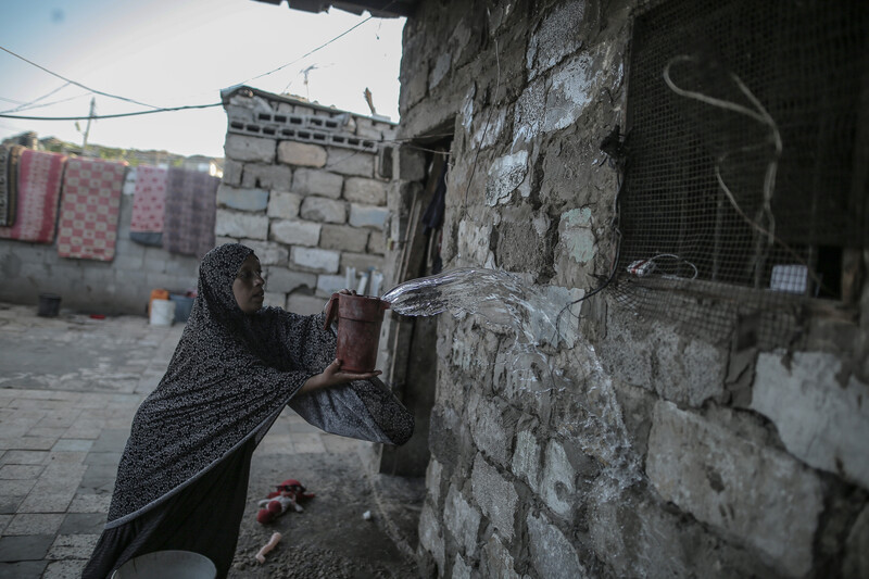 A woman throws a bucketful of water onto a wall