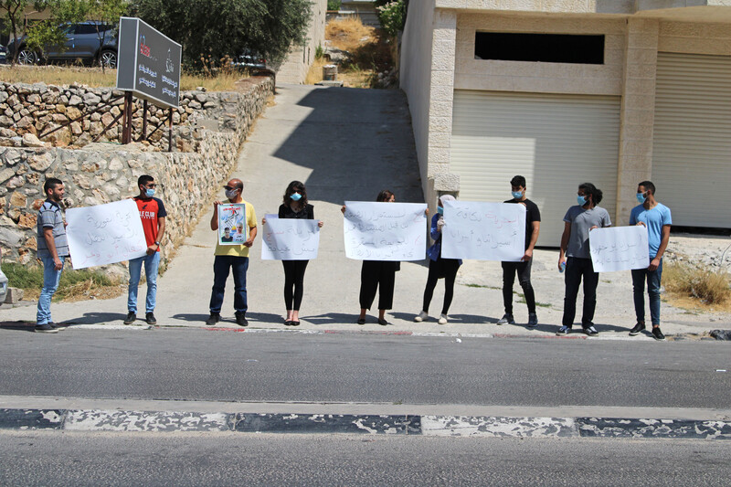People stand next to each other on the street holding signs