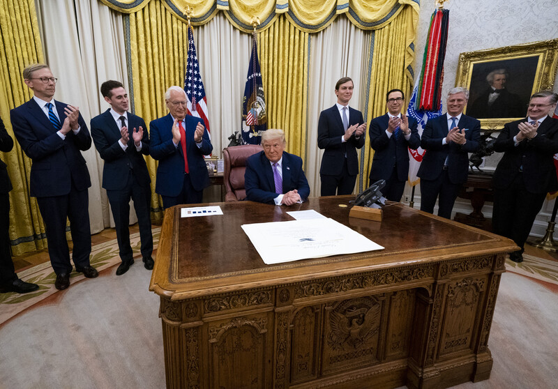 Man sits behind office surrounded by men