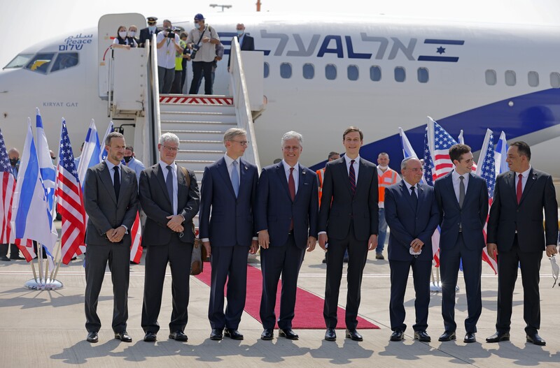Men in suits stand in one line before airplane