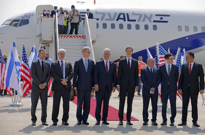 Men in suits stand in one line before airplane 