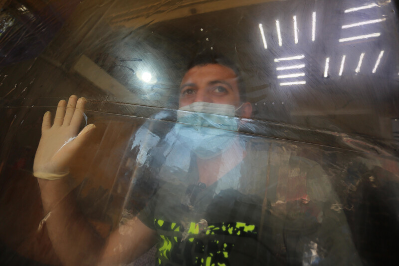 Man in mask places gloved hand on protective screen