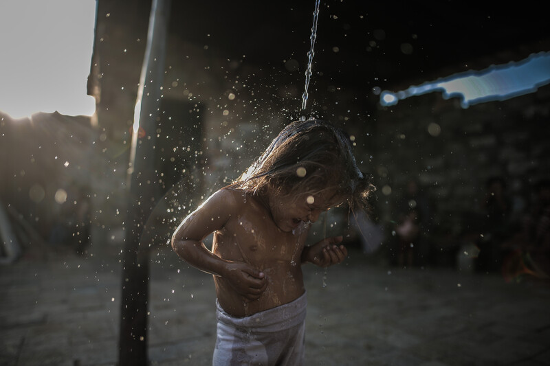 A girl laughs as water is poured over her head