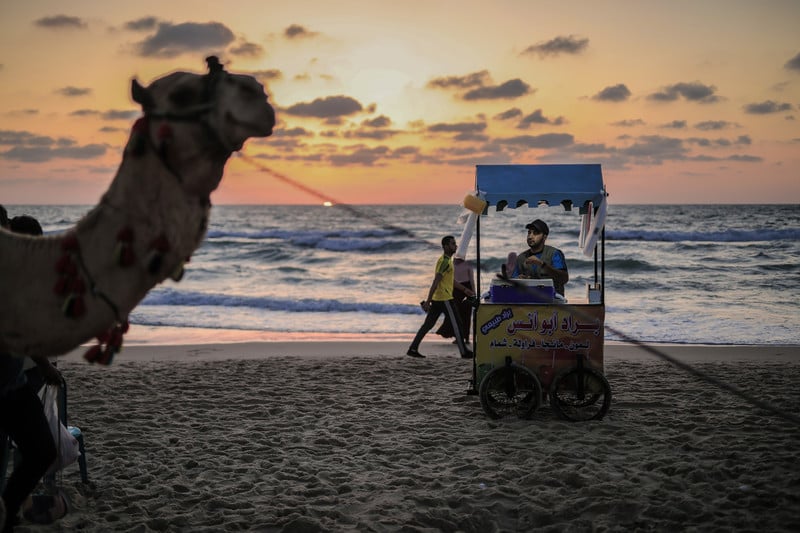 The sun sets over the sea behind a vendor on Gaza beach