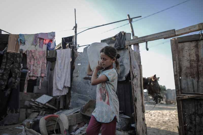 A girl carries a bucket of water on her shoulder