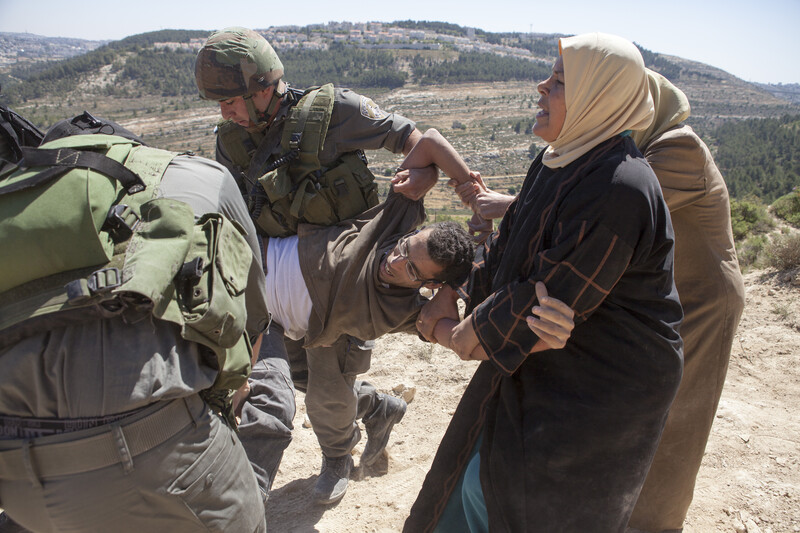 A young man is carried by soldiers and pulled by two civilian women