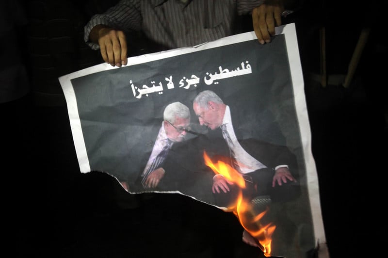 Man holds burning poster of two men 