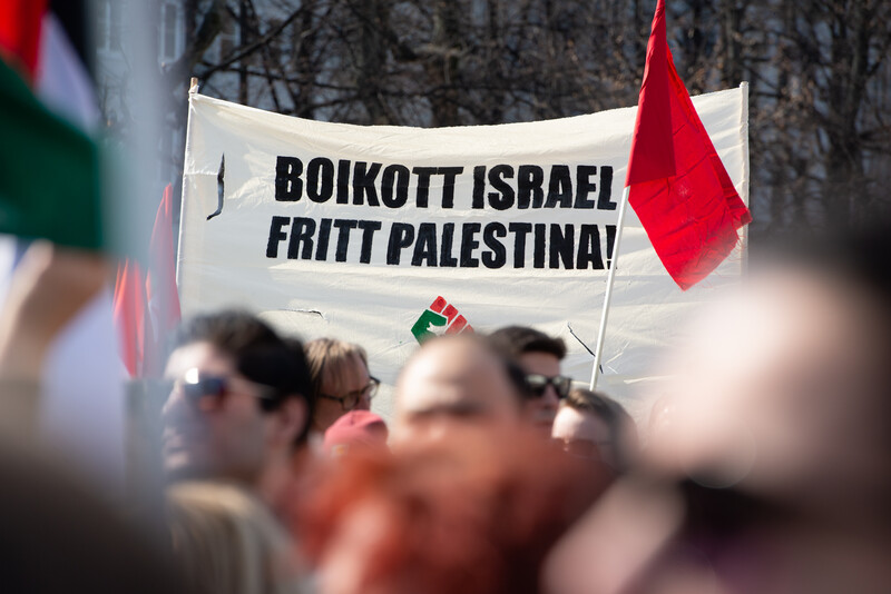 Crowd stands in banner calling for boycott of Israel and freedom for Palestine