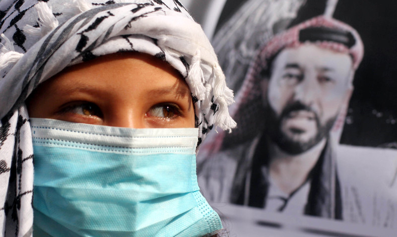 Child wearing protective mask near poster of a man