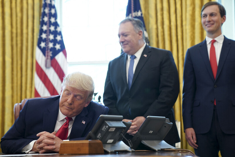 Man sits on a desk surrounded by others 