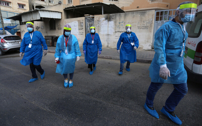 Five nurses in protective gear and masks walk down a street