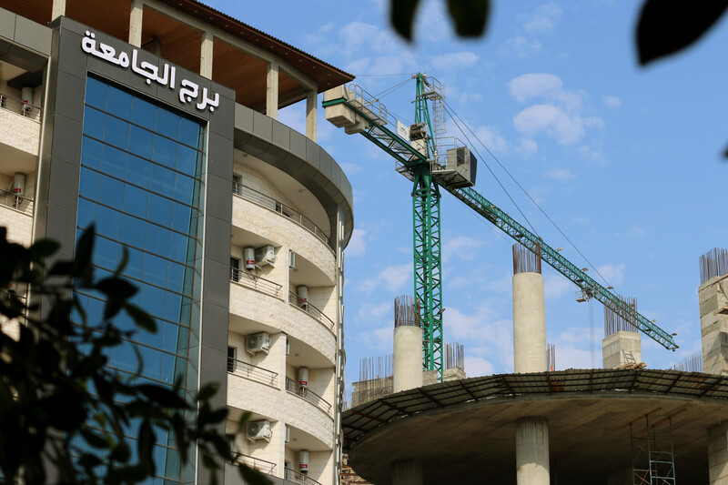 A huge crane looms behind a modern glass-fronted building