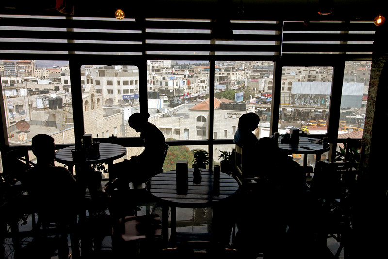 The silhouettes of a number of people at different tables stand out against the panoramic view behind them