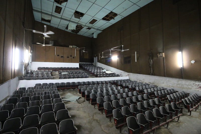 A disused hall with dozens of seats all front facing
