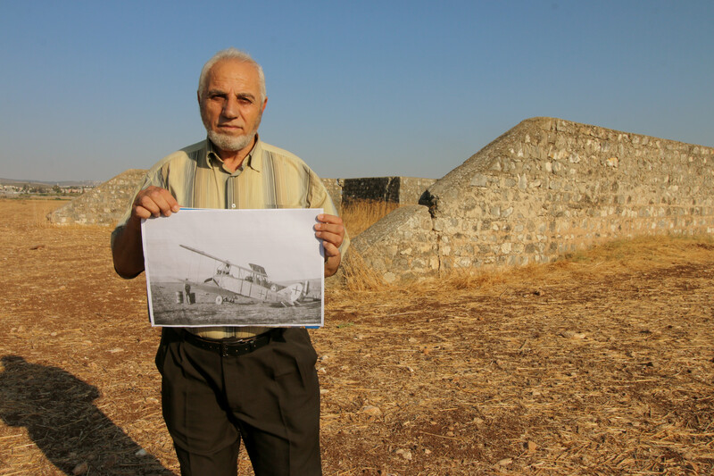 A man stands holding a black and white photo