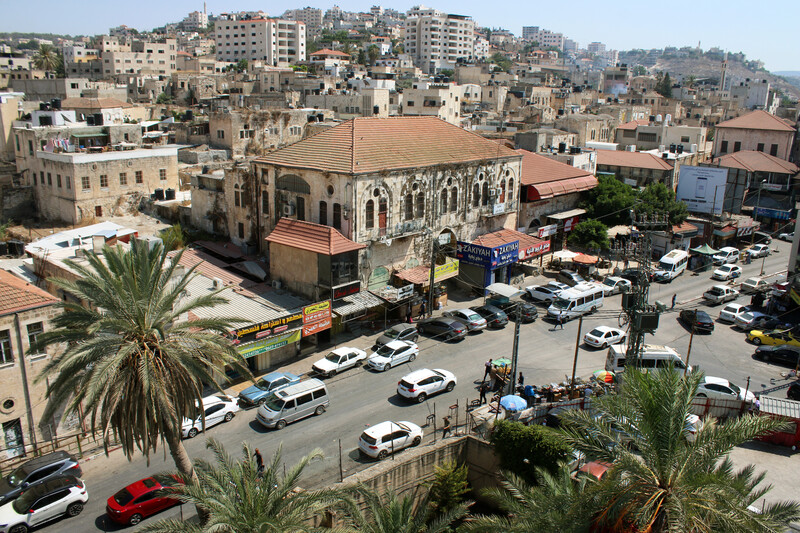 A view over a city, with buildings, traffic and just two trees