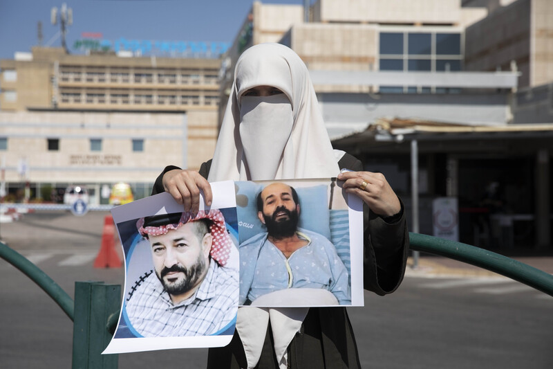 Woman wearing a veil holds two portraits of a man