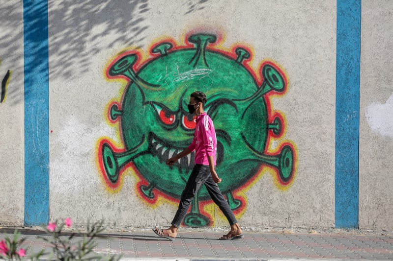 Man walks by a mural of a large virus particle 