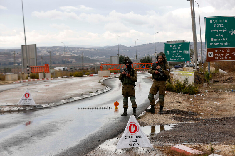 Two heavily armed soldier stand on the side road