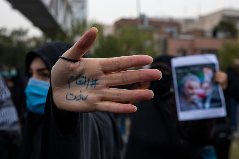 Woman holds hand up as others stand nearby with posters