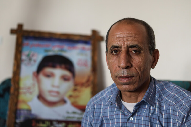 A man sits in front of a framed picture of a boy